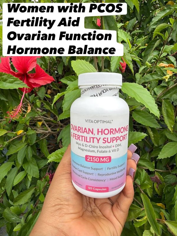 Vita Optimal Ovarian, Hormone & Fertility Support 2150mg A bottle of Vita Optimal Ovarian, Hormone & Fertility Support, 120 capsules, held in front of a hibiscus plant